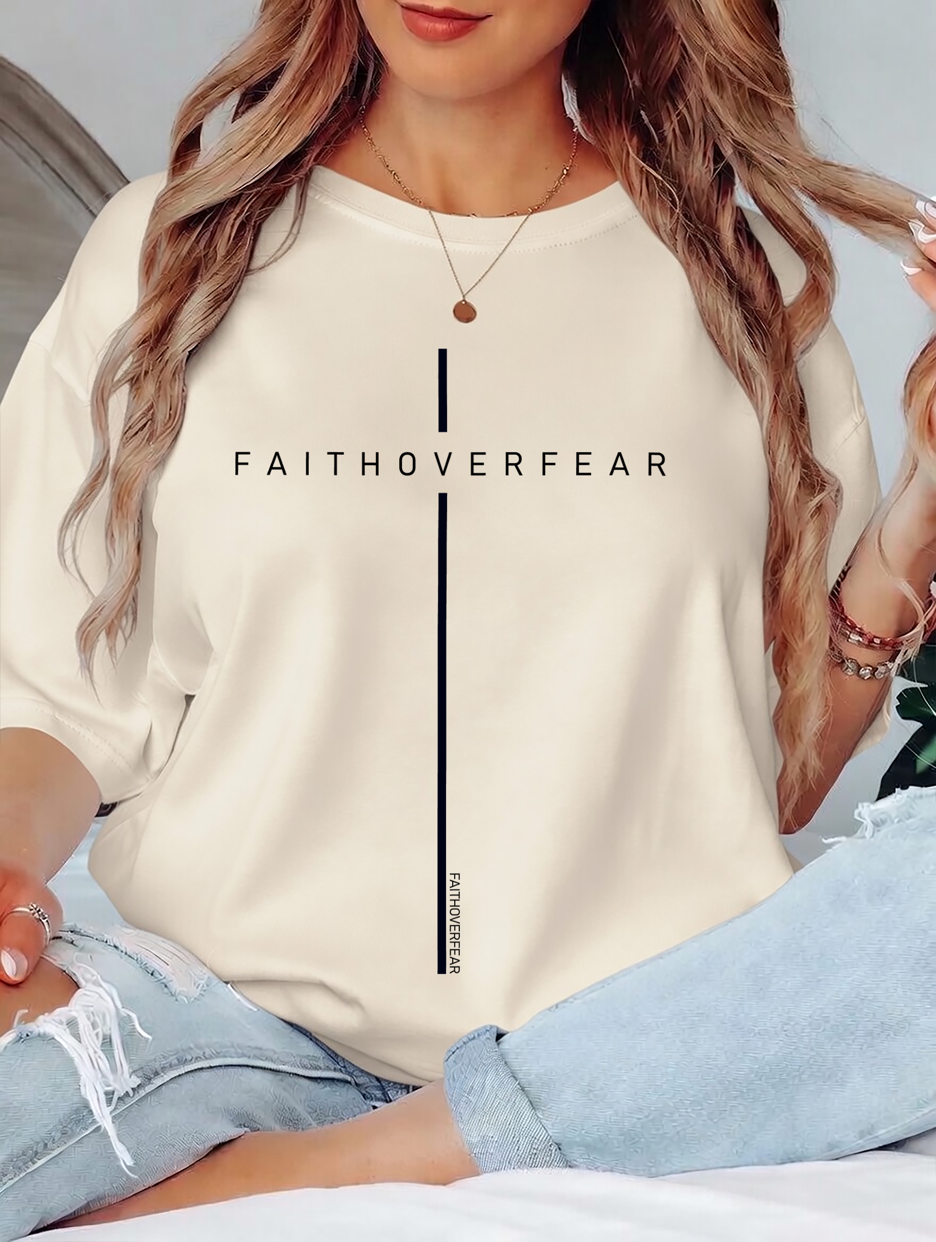 Person wearing a beige shirt with 'FAITHOVERFEAR' text design.