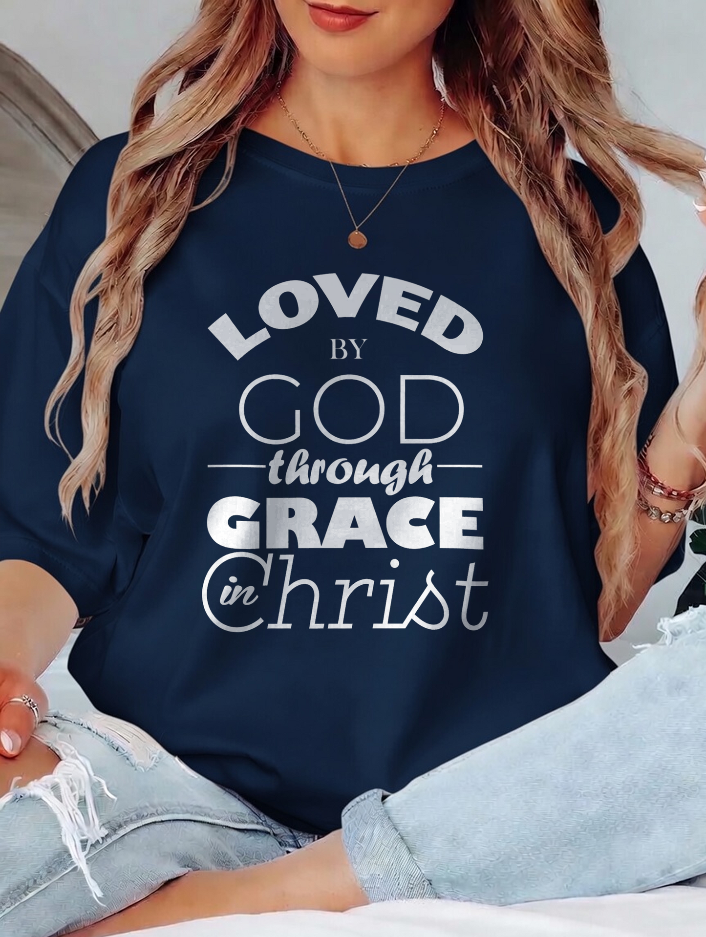Person wearing a navy blue sweatshirt with text 'LOVED by GOD through GRACE in Christ'.