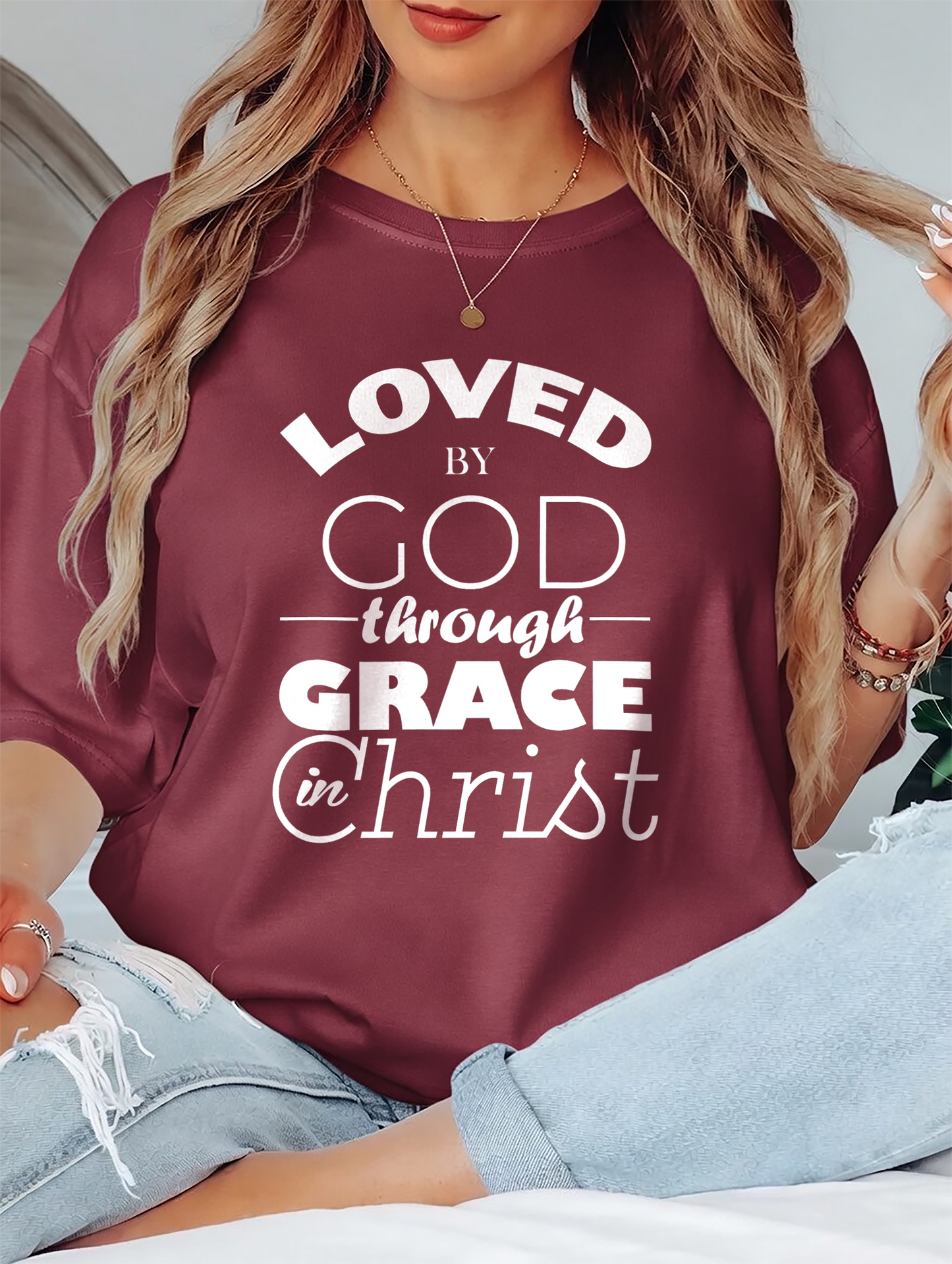 Person wearing a maroon shirt with text 'LOVED by GOD through GRACE in Christ'.
