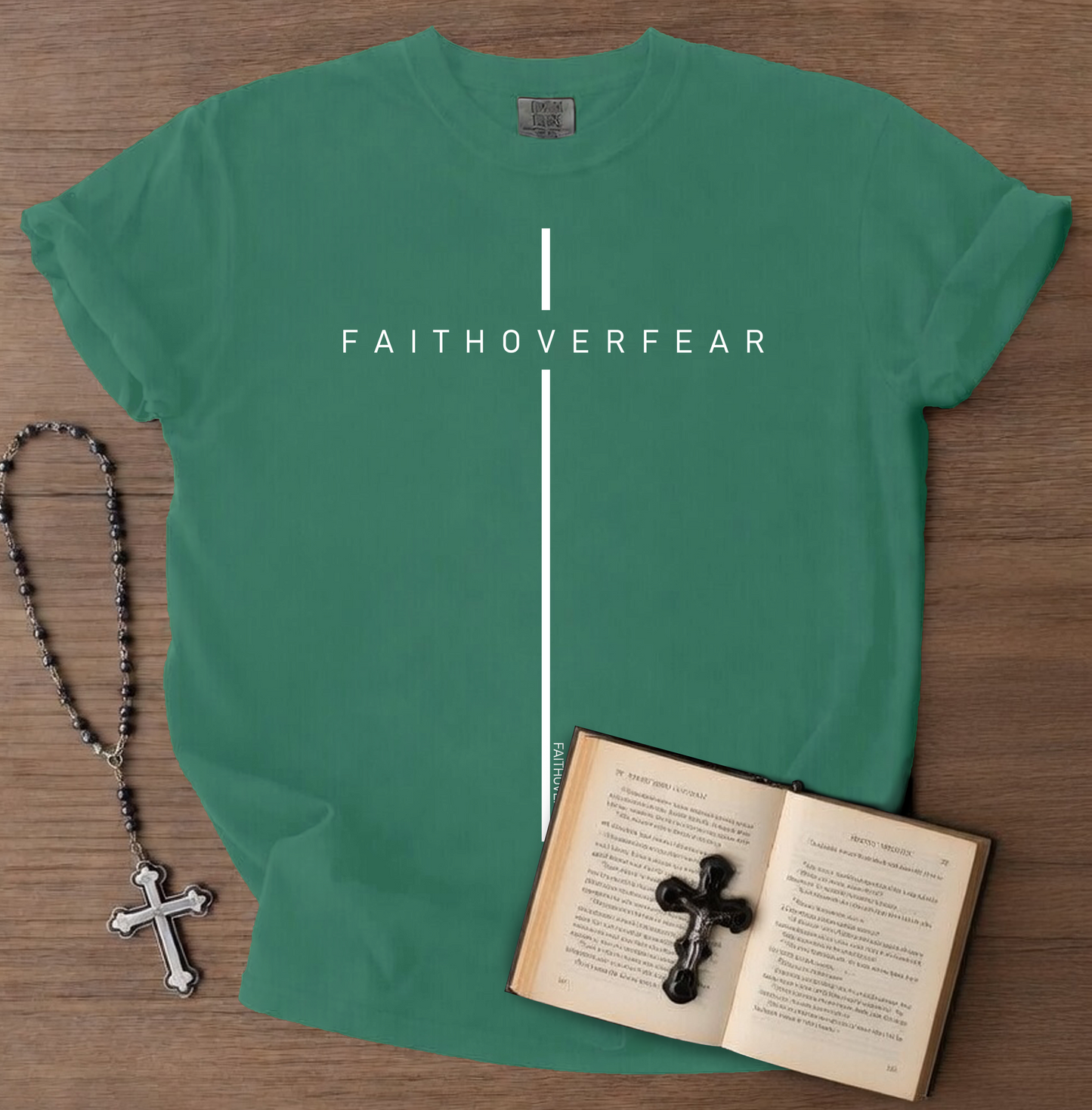 Green t-shirt with 'FAITHOVERFEAR' text, next to a rosary and open book on a wooden surface