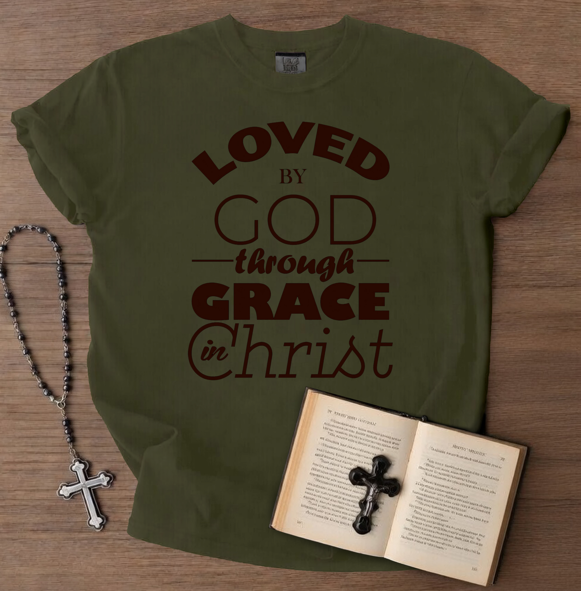 Green t-shirt with 'FAITHOVERFEAR' text, rosary, and open book on a wooden surface