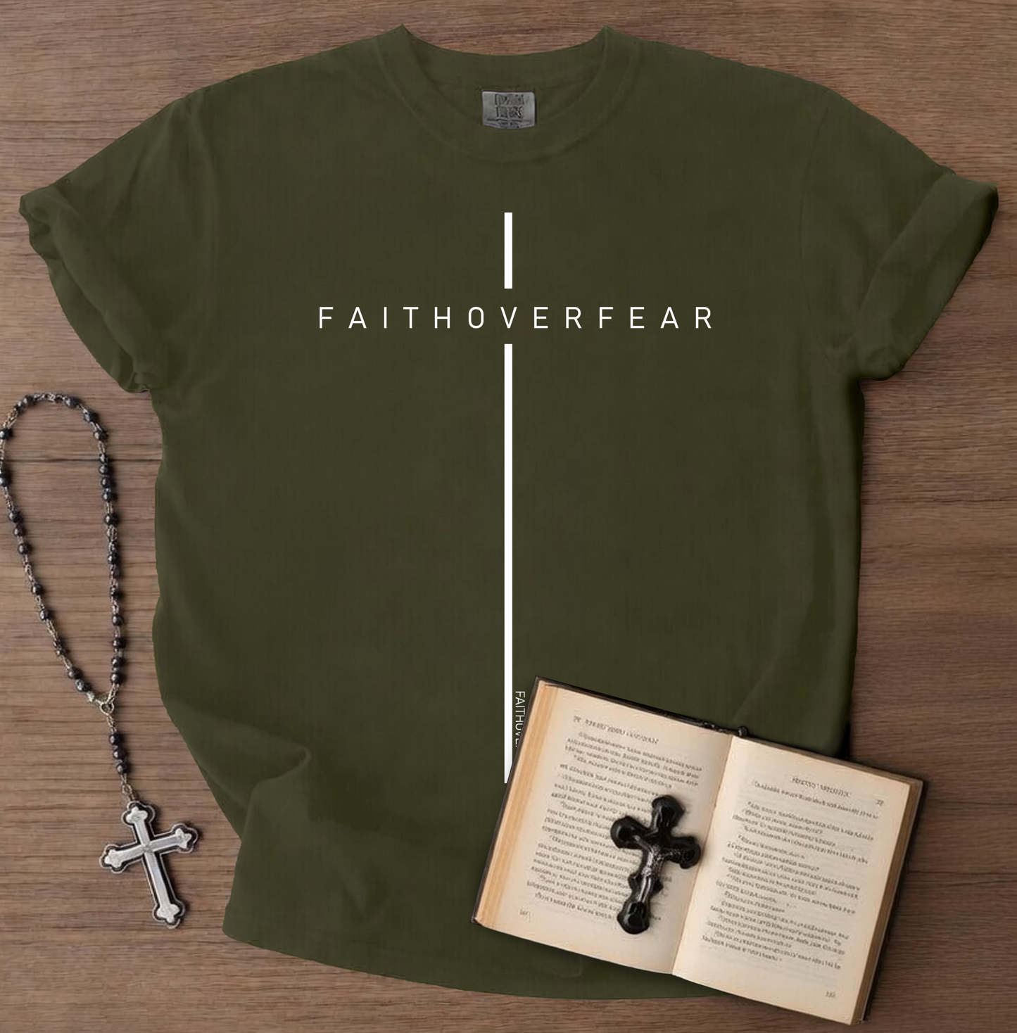 Green t-shirt with 'FAITHOVERFEAR' text, rosary, and open book on a wooden surface