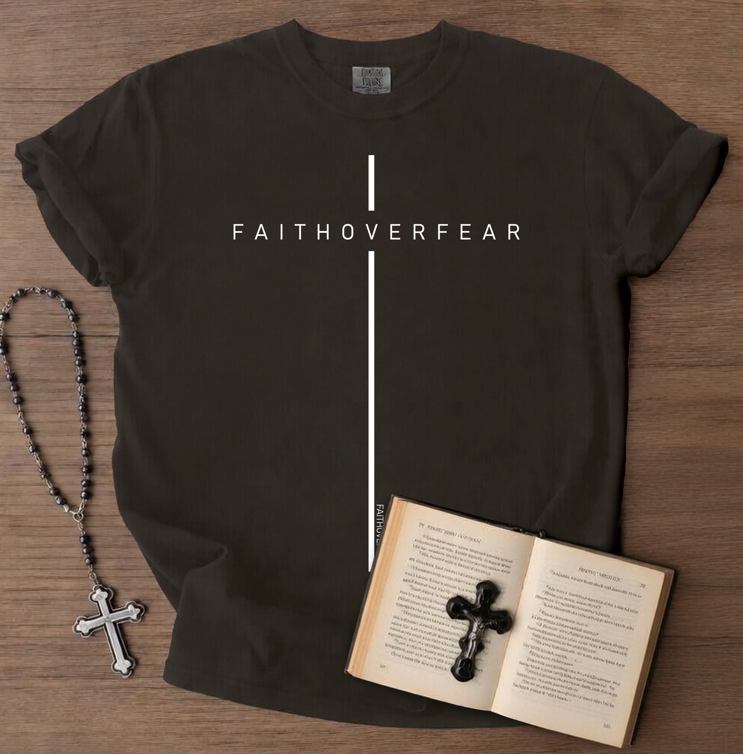 Black t-shirt with 'FAITHOVERFEAR' text, rosary, and open book on a wooden surface