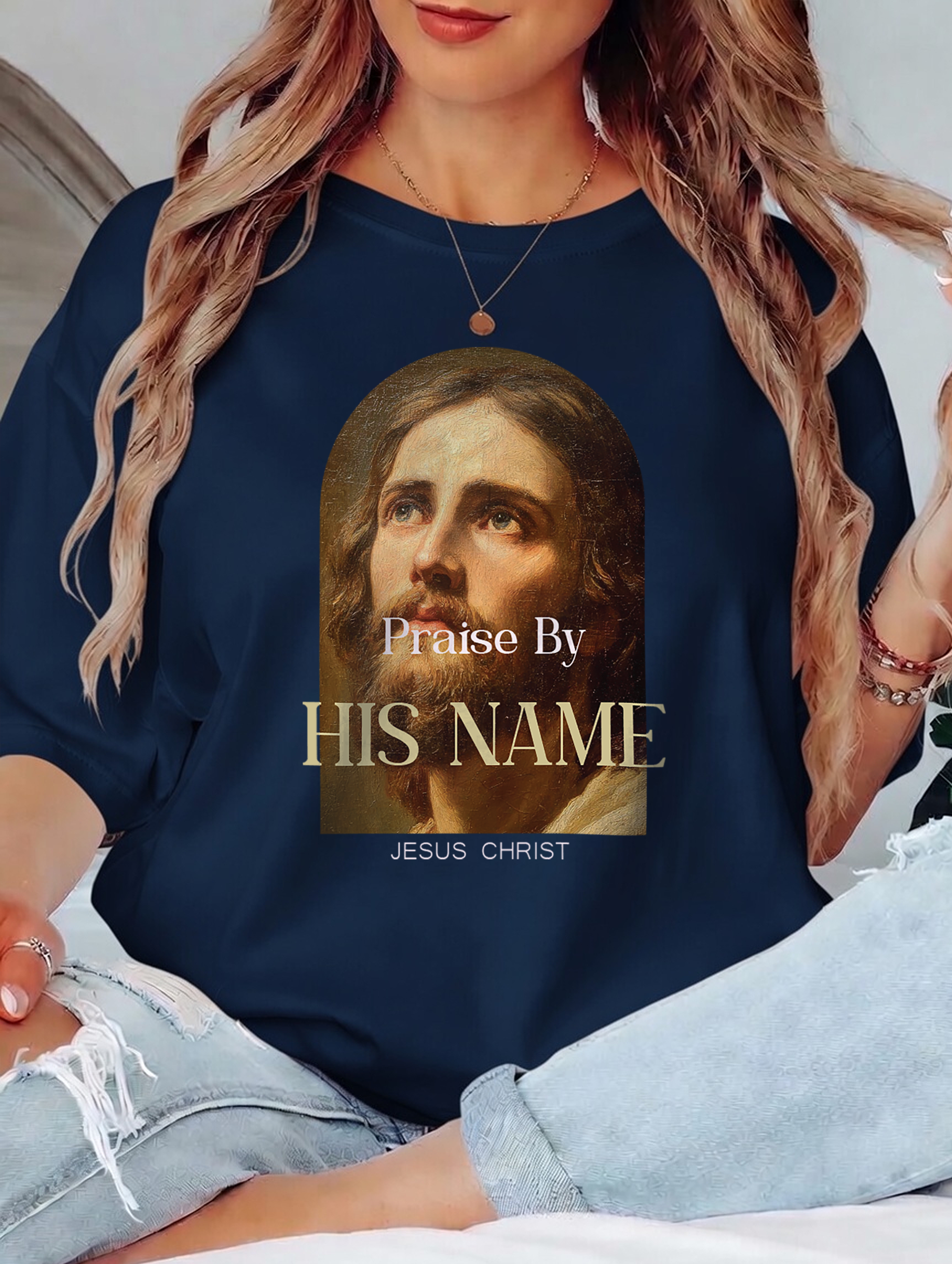 Navy blue shirt with a graphic of Jesus Christ and text 'Praise By HIS NAME JESUS CHRIST' worn by a person.
