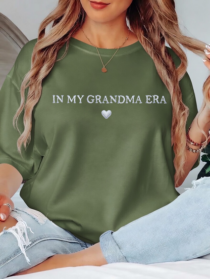Person wearing a green sweatshirt with 'IN MY GRANDMA ERA' text and heart symbol.