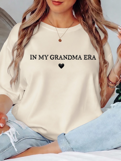 Person wearing a white sweatshirt with 'IN MY GRANDMA ERA' text and a heart symbol.